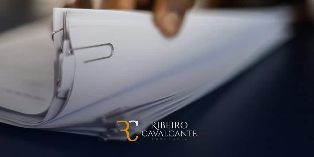Pilha de documentos grampeados com logotipo da Ribeiro Cavalcante Advocacia ao fundo, ilustrando serviços jurídicos.