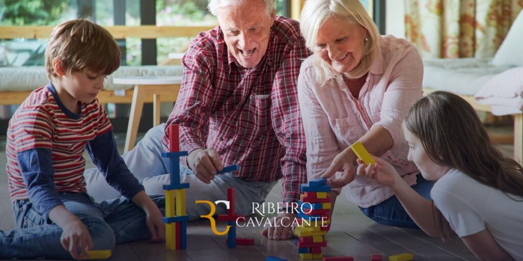 Avós brincando com blocos de construção com seus netos. Logo da Ribeiro Cavalcante Advogados ao centro.