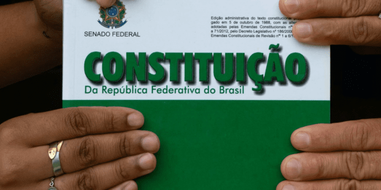 Pessoa segurando um exemplar da Constituição da República Federativa do Brasil, edição do Senado Federal.