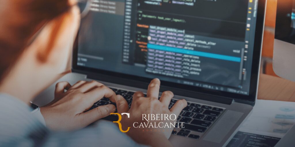 Pessoa codificando no laptop com o logo do escritório Ribeiro Cavalcante Advocacia visível na imagem.