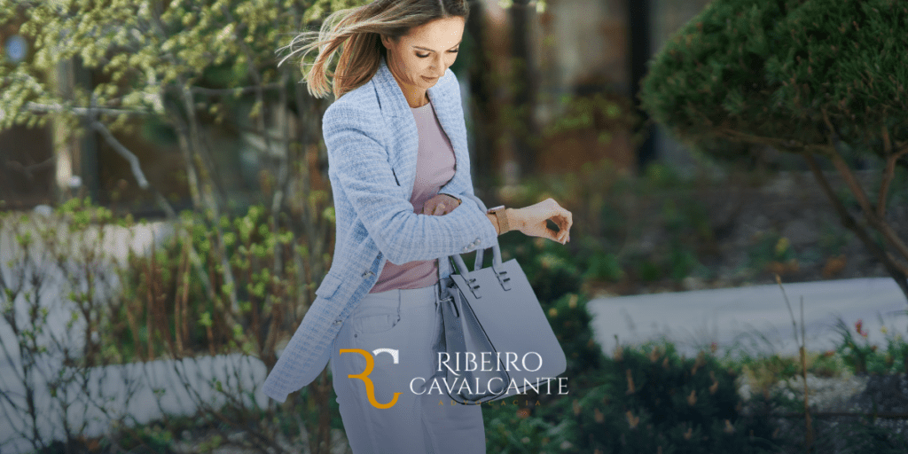 Mulher olhando para o relógio, usando blazer azul e bolsa cinza, com logotipo da Ribeiro Cavalcante Advocacia.