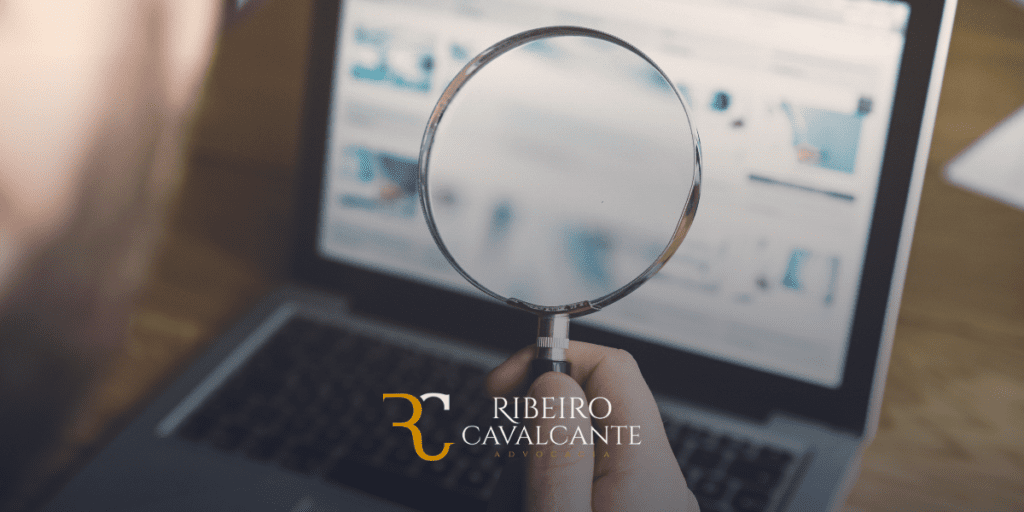 Lupa em frente a um laptop desfocado, com o logotipo Ribeiro Cavalcante Advocacia no canto inferior da imagem.