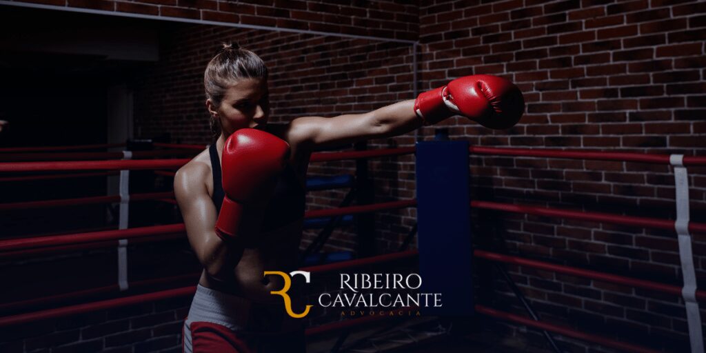 Mulher boxeadora treinando no ringue com luvas vermelhas, logotipo da Ribeiro Cavalcante Advocacia ao redor.