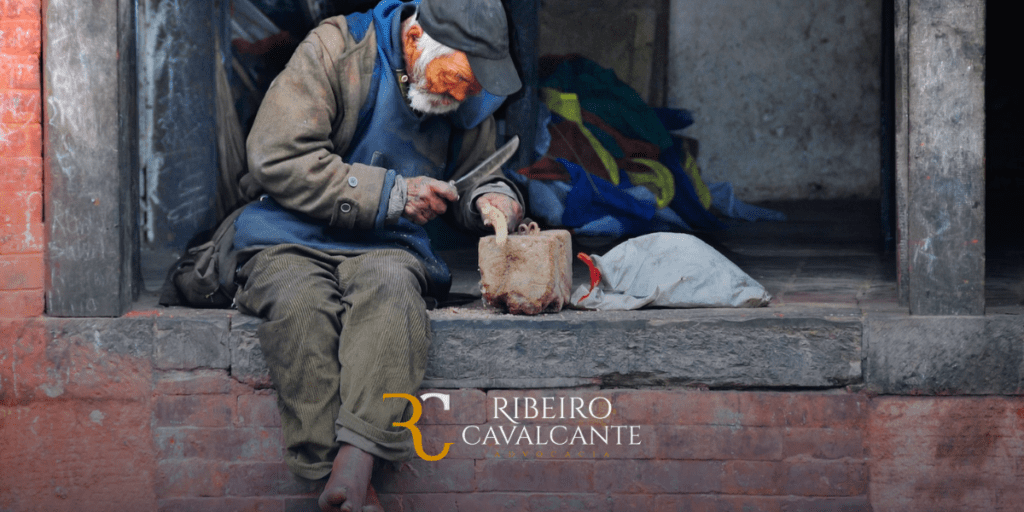 Homem idoso sentado na calçada, esculpindo madeira em ambiente urbano. Logotipo Ribeiro Cavalcante Advocacia.