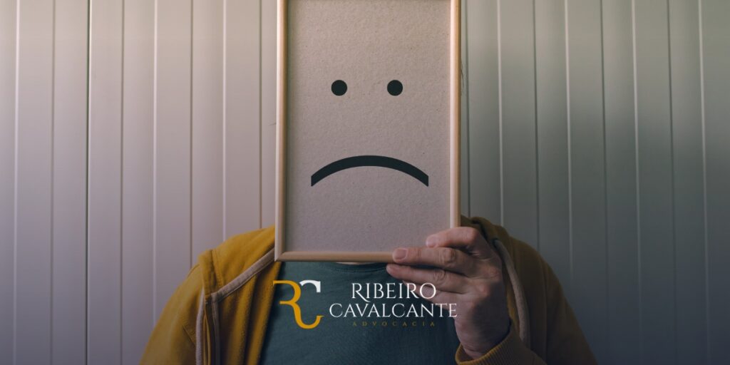 Homem segurando quadro com rosto triste, logo Ribeiro Cavalcante Advocacia, especialistas em Direito Previdenciário e Cível.