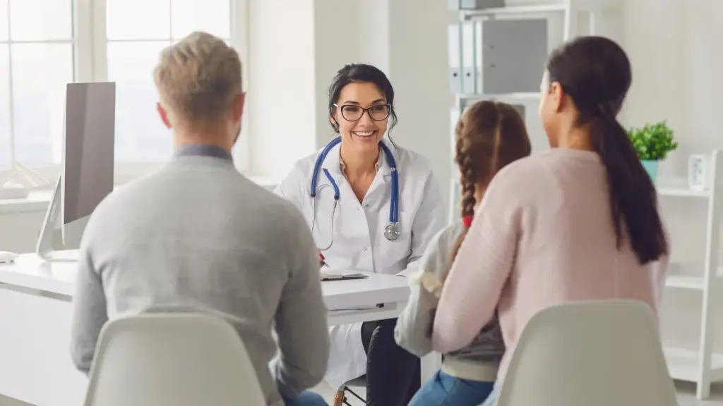 Médica sorridente conversa com casal em consultório