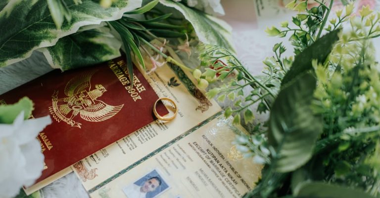 Passaporte vermelho, certidão com foto e aliança de ouro sobre mesa decorada com folhas verdes. — Foto: Rizki Koto