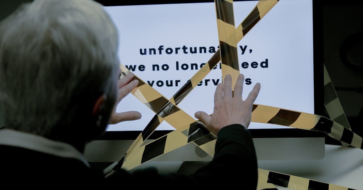 Homem olhando monitor com mensagem de desligamento profissional e fitas de isolamento zebradas à frente. — Foto: Ron Lach