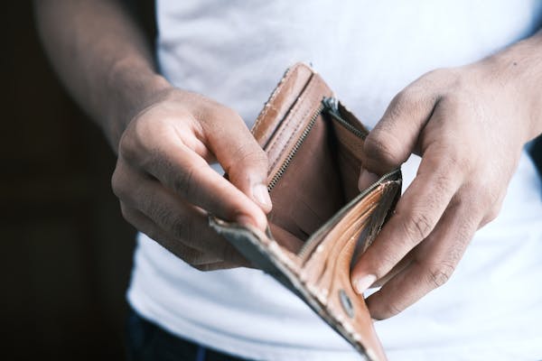 Mãos segurando carteira vazia, representando o prejuízo financeiro causado pelas apostas online