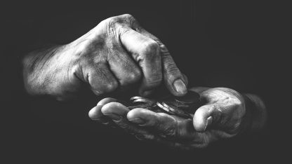 Foto em preto e branco de mãos idosas e calejadas segurando e contando moedas em um fundo escuro. — Foto: Frantisek_Krejci