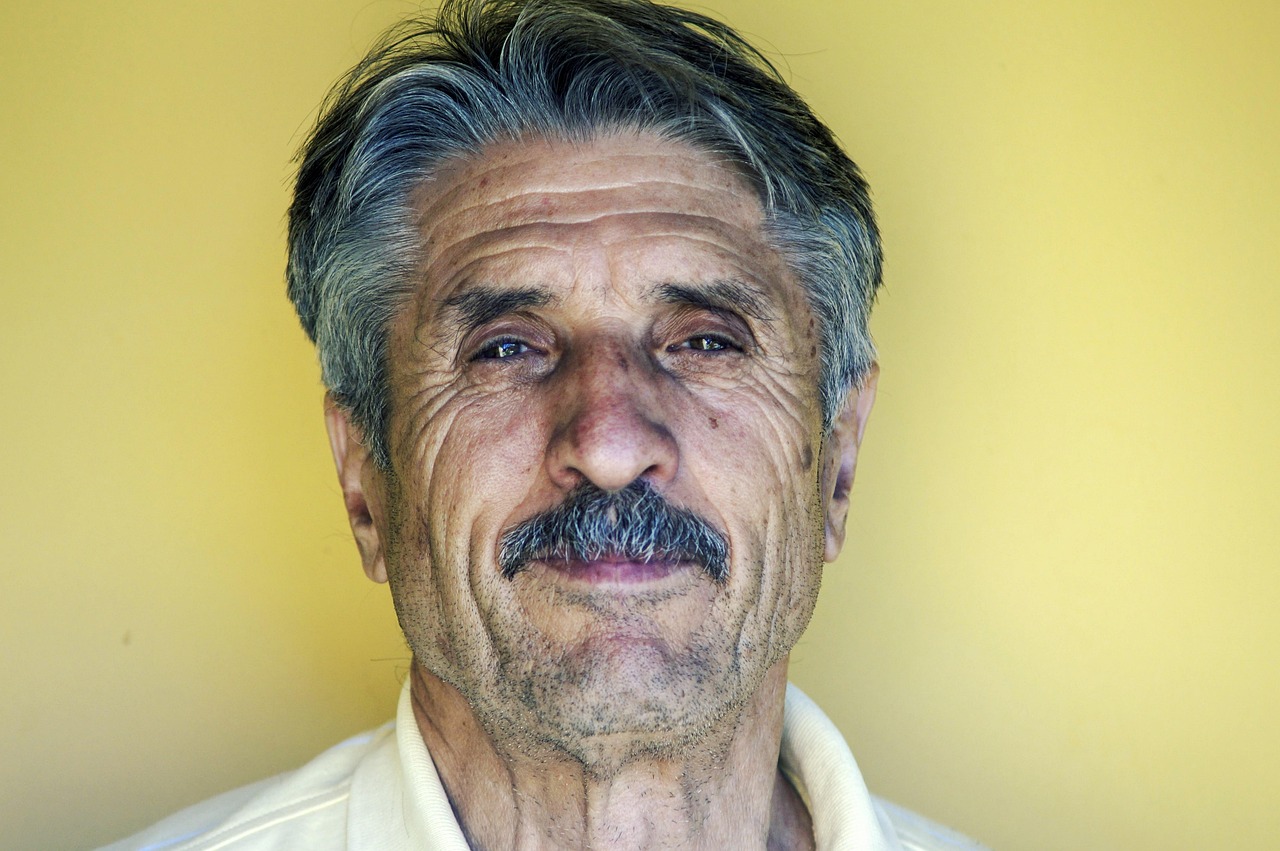 Bpc loas 78327 1772276683 Retrato de um homem idoso com bigode e cabelos grisalhos olhando para a câmera em fundo amarelo. — foto: pexels