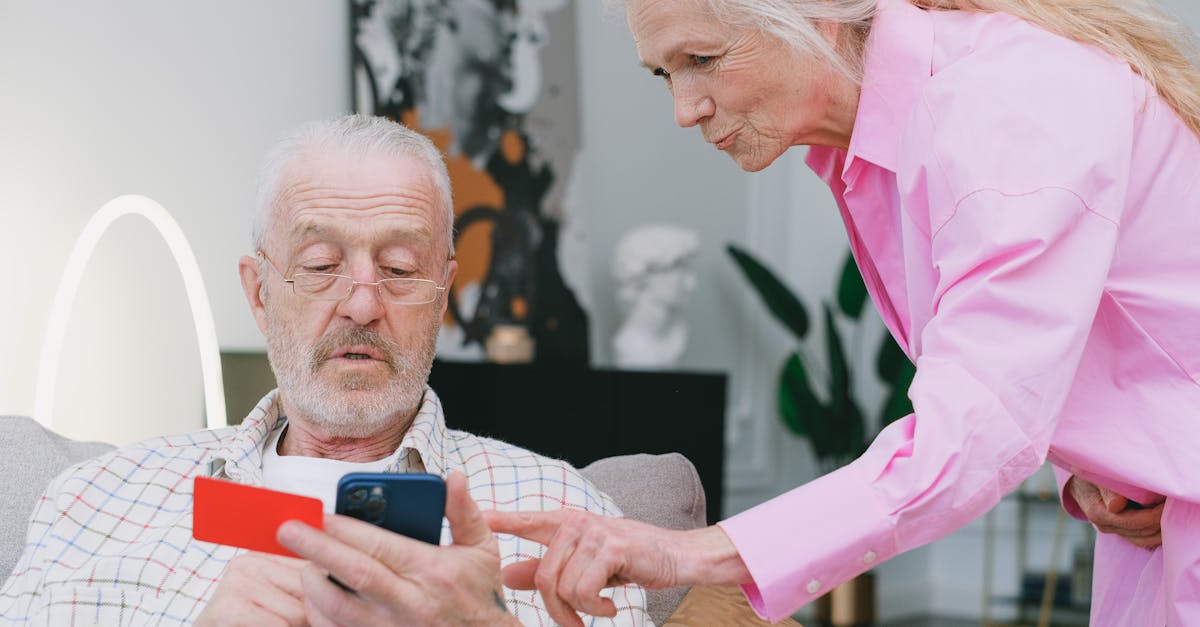 Homem idoso segurando cartão e celular enquanto mulher observa, representando gestão financeira na terceira idade. — Foto: SHVETS production
