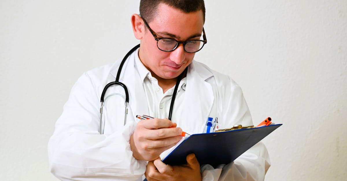 Médico de jaleco branco e estetoscópio escrevendo em uma prancheta com fundo branco. — Foto: GIUSEPPE DE BERGOLIS