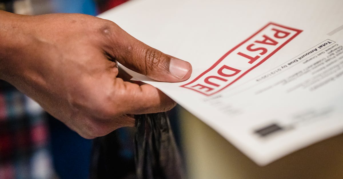 Mão segurando um documento com carimbo vermelho escrito 'Past Due', indicando conta vencida. — Foto: Nicola Barts
