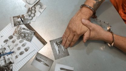 Mãos algemadas sobre uma mesa com fotos de evidências criminais, impressões digitais e documentos de investigação. — Foto: RDNE Stock project