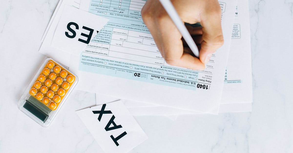 Mão segurando caneta e preenchendo formulários sobre uma mesa branca ao lado de uma calculadora. — Foto: Nataliya Vaitkevich