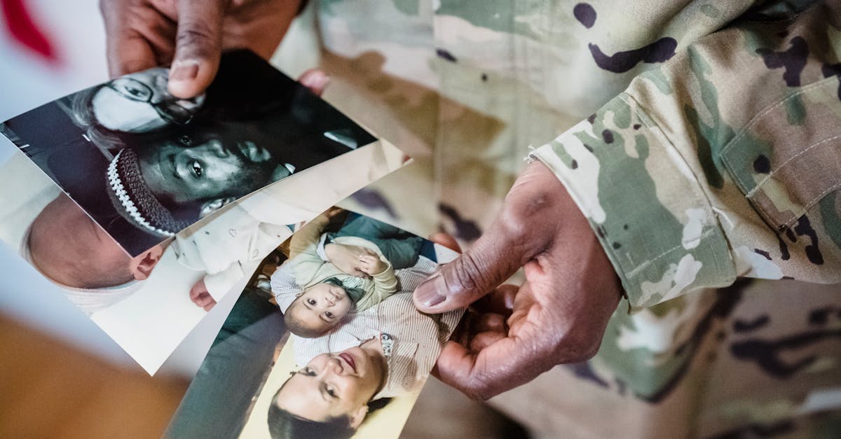 Pessoa com farda militar segurando fotos de sua família, com foco nas mãos e nas fotografias. — Foto: George Pak