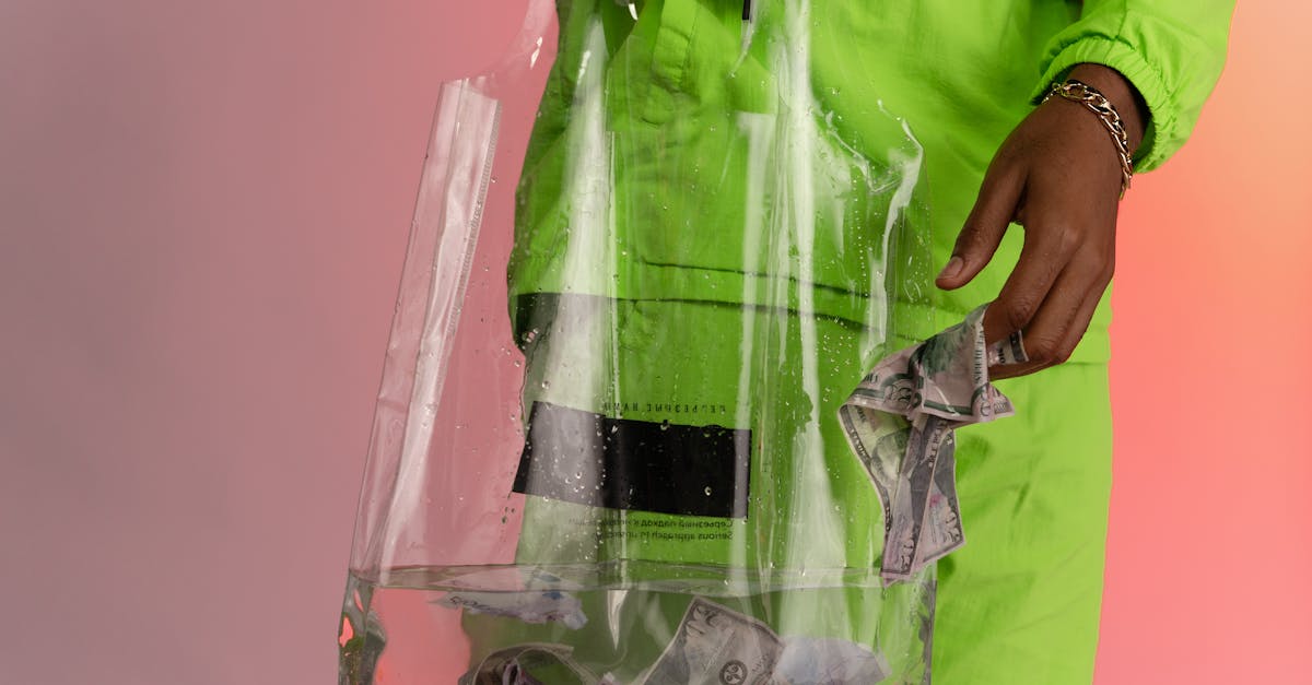 Pessoa com roupa verde colocando notas de dólar dentro de uma sacola plástica transparente com água. — Foto: cottonbro studio