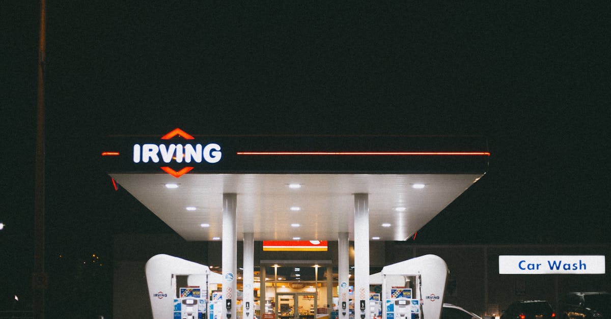 Fachada iluminada de um posto de combustíveis à noite com letreiro da marca e área de lavagem de carros ao fundo. — Foto: Erik Mclean