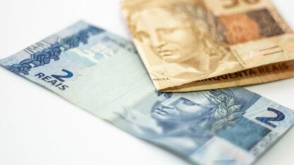 Cédulas de dois e cinquenta reais brasileiros sobre uma superfície branca em ângulo aproximado. — Foto: Daniel Dan