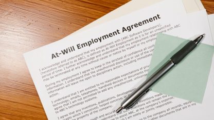Contrato de trabalho sobre mesa de madeira com uma caneta e bloco de notas adesivo. — Foto: RDNE Stock project