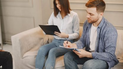 Homem e mulher sentados em um sofá assinando documentos e formulários em pranchetas. — Foto: Gustavo Fring