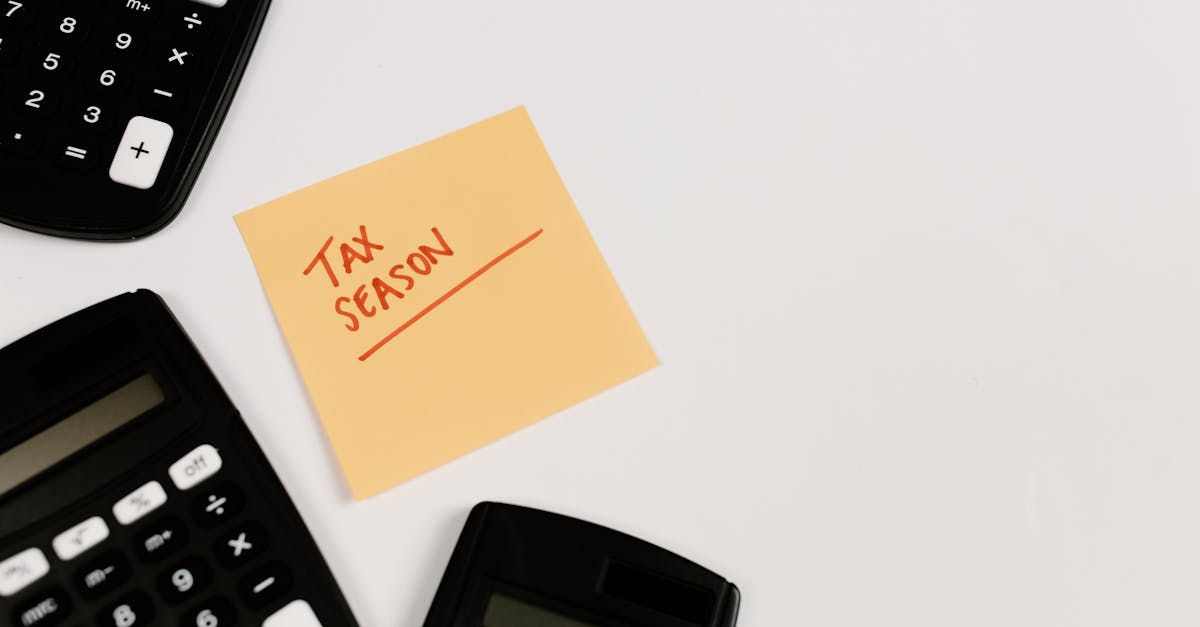 Calculadoras sobre uma mesa branca ao lado de um bloco de notas adesivo com a inscrição Tax Season. — Foto: Tara Winstead