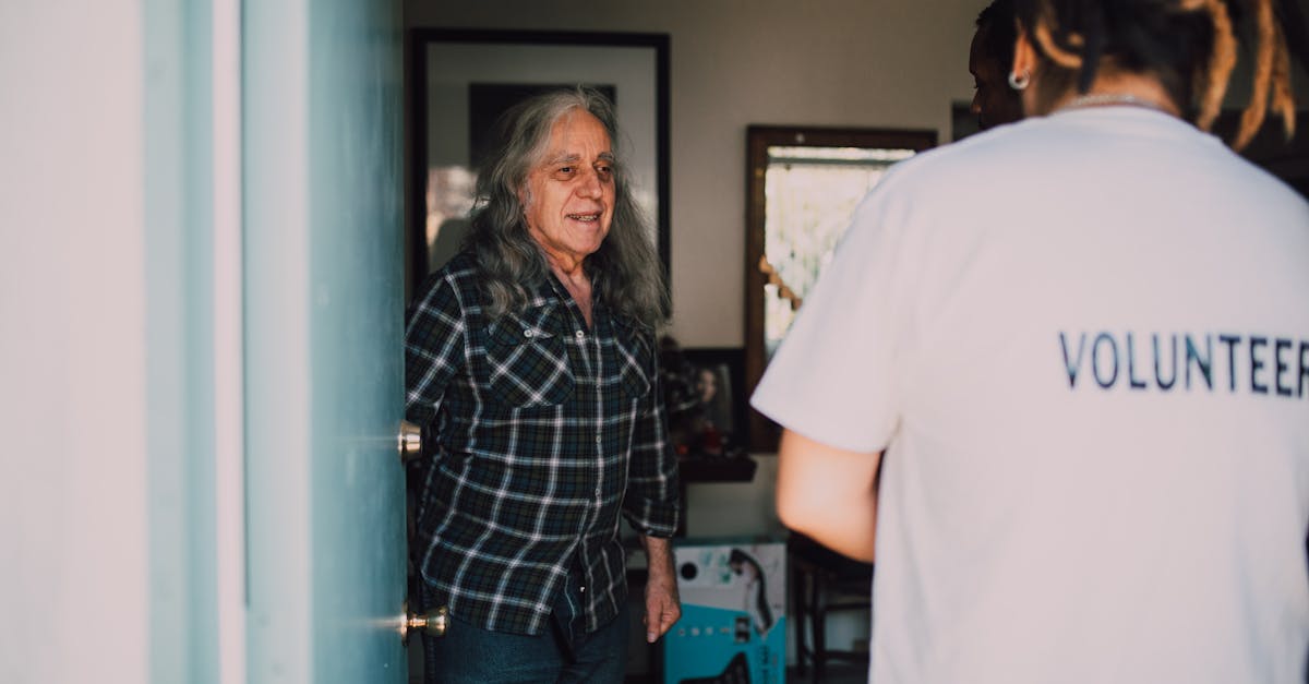 Pessoa voluntária conversando com um senhor idoso na porta de uma residência. — Foto: RDNE Stock project