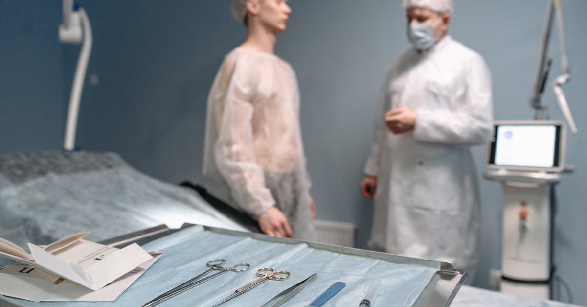 Médico em traje cirúrgico conversando com paciente em consultório com instrumentos médicos em primeiro plano. — Foto: Pavel Danilyuk