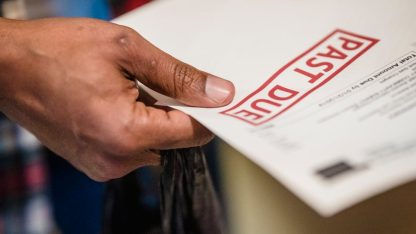 Mão segurando documento com carimbo vermelho escrito Past Due, indicando conta vencida. — Foto: Nicola Barts