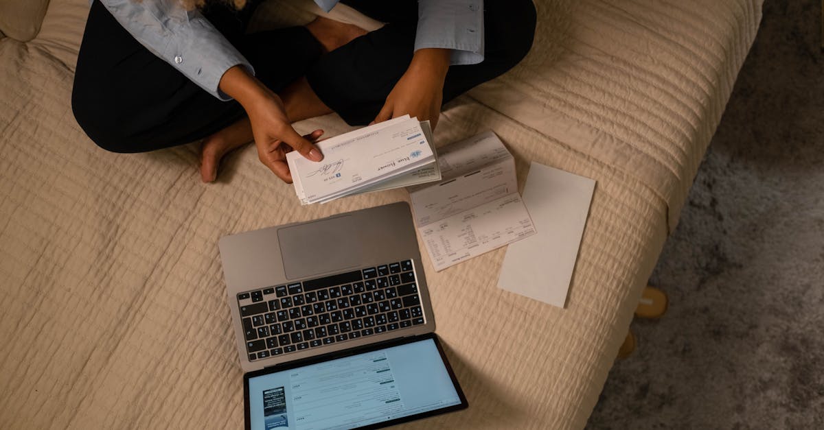 Pessoa sentada com notebook analisando diversos boletos e faturas de papel sobre uma superfície clara. — Foto: cottonbro studio