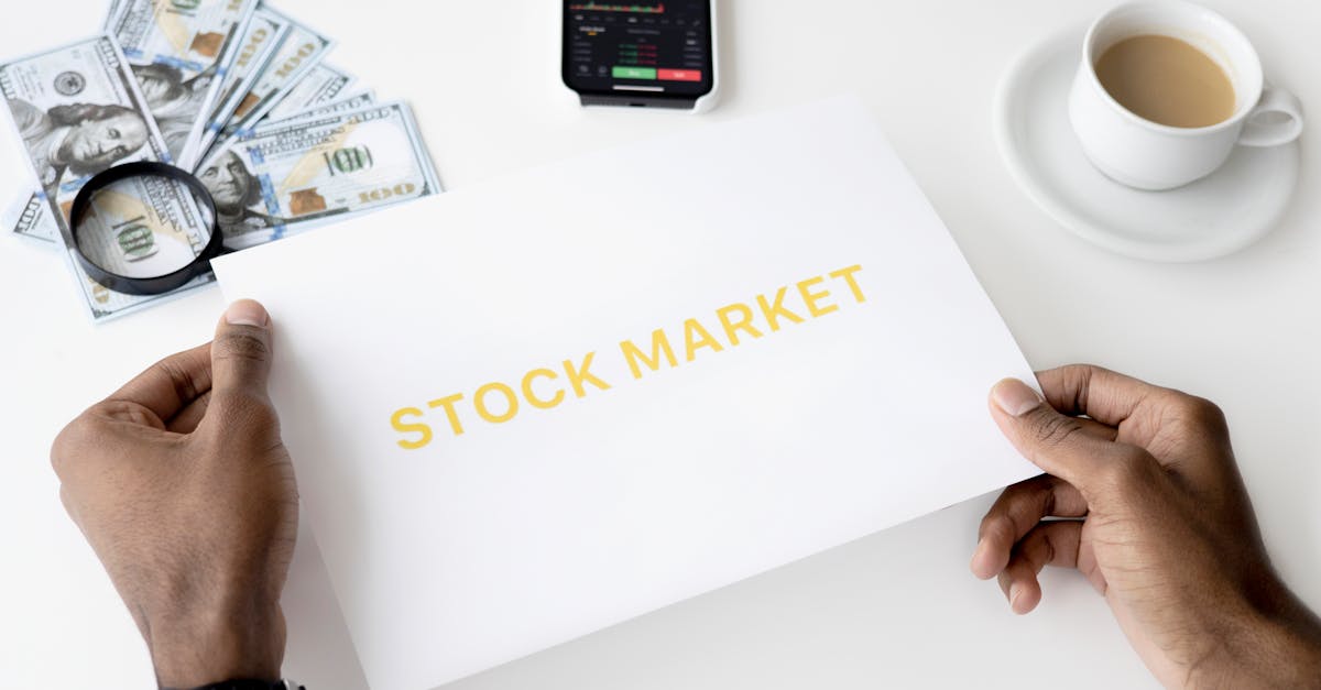 Mãos segurando papel escrito Stock Market sobre mesa com notas de dólar, lupa, celular e uma xícara de café. — Foto: Hanna Pad