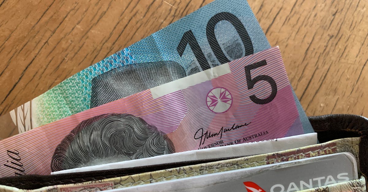 Cédulas de dinheiro e cartões de crédito saindo de uma carteira sobre uma mesa de madeira. — Foto: Miles Burke