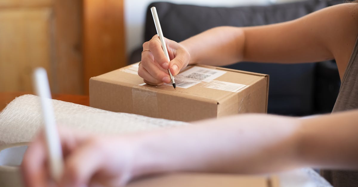 Pessoa escrevendo em uma caixa de papelão para envio postal, representando a devolução de uma compra. — Foto: Kampus Production