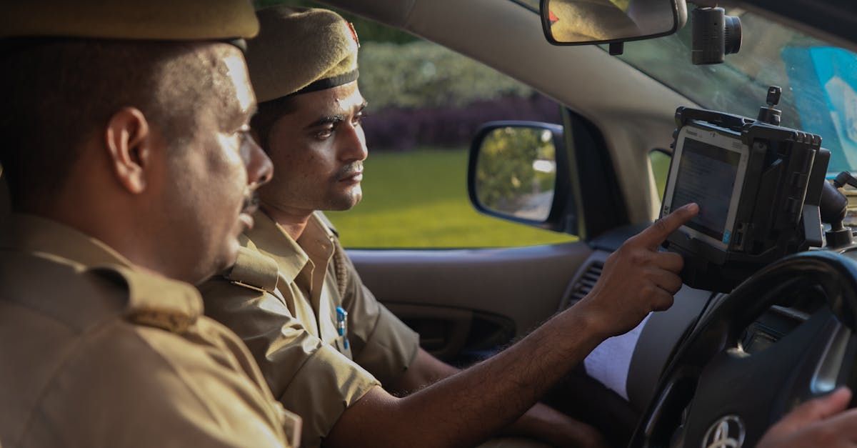 Dois policiais fardados dentro de uma viatura operando um tablet ou terminal digital no painel do veículo. — Foto: 112 Uttar Pradesh