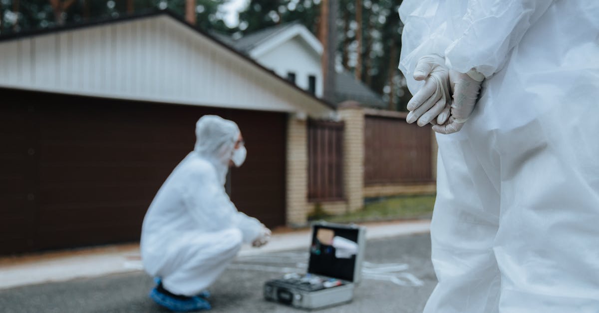 Peritos criminais em trajes brancos de proteção analisando uma cena de crime em frente a uma residência. — Foto: cottonbro studio