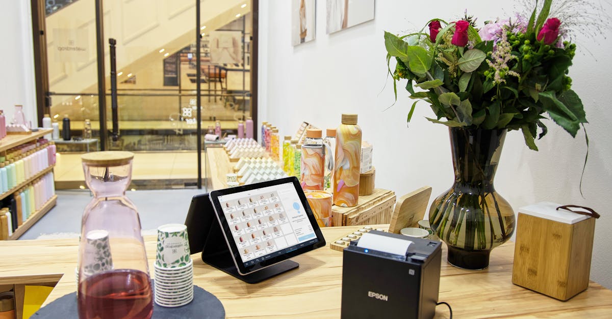 Devolucao de produto 81646 1774364572 Balcão de loja com tablet de vendas, impressora de recibos, garrafas e um vaso de flores ao fundo. — foto: tom tillhub