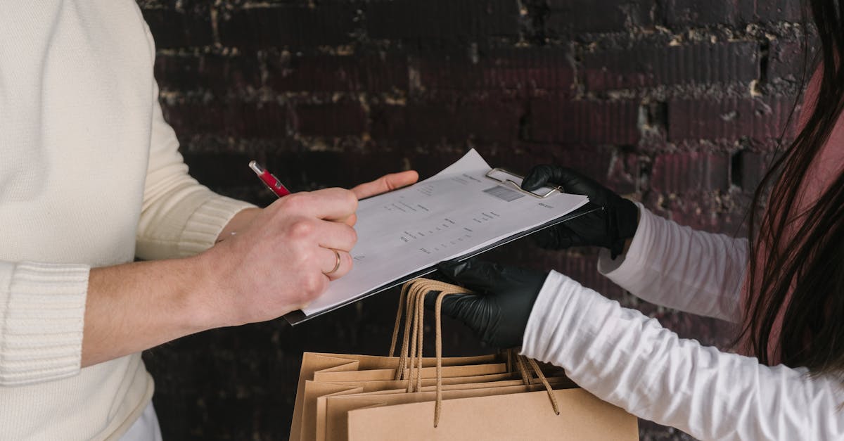 Pessoa assinando formulário em prancheta segurada por atendente com sacolas de compras de papel. — Foto: Mikhail Nilov