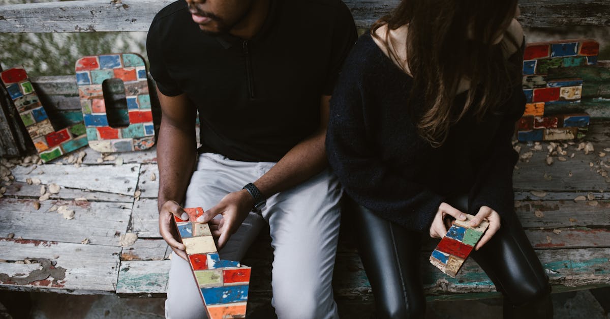 Homem e mulher sentados em um banco rústico, segurando letras coloridas quebradas que formam a palavra LOVE. — Foto: RDNE Stock project