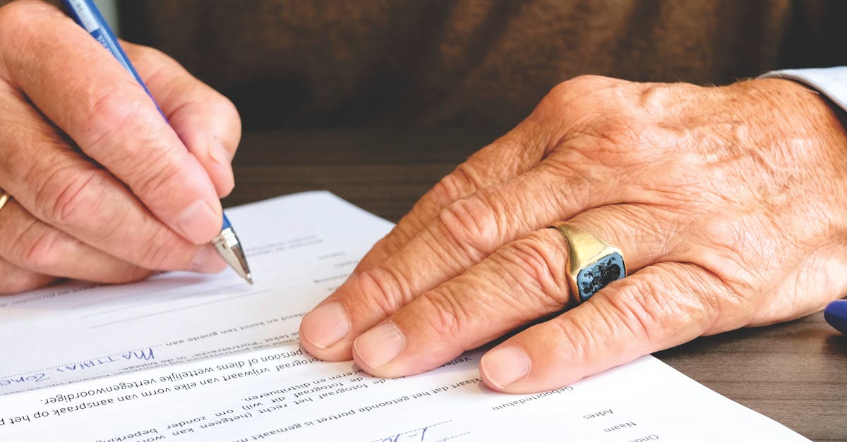 Close das mãos de uma pessoa idosa assinando um documento oficial com uma caneta sobre uma mesa de madeira. — Foto: Matthias Zomer