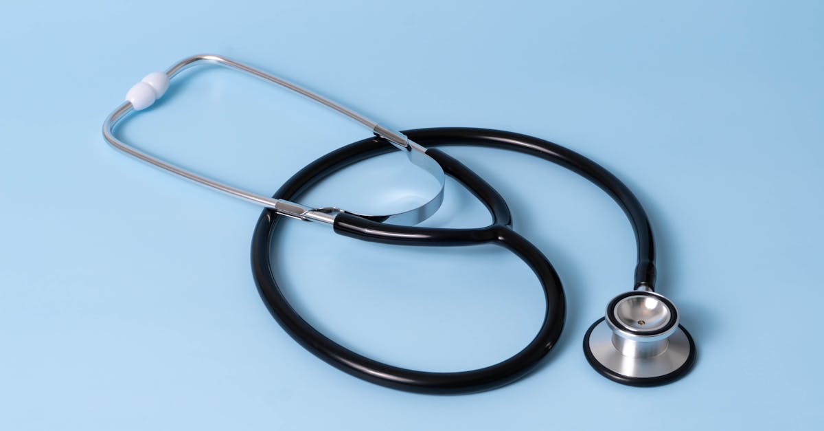 Um estetoscópio médico preto e prata repousando sobre uma superfície azul clara uniforme. — Foto: Etatics Inc.