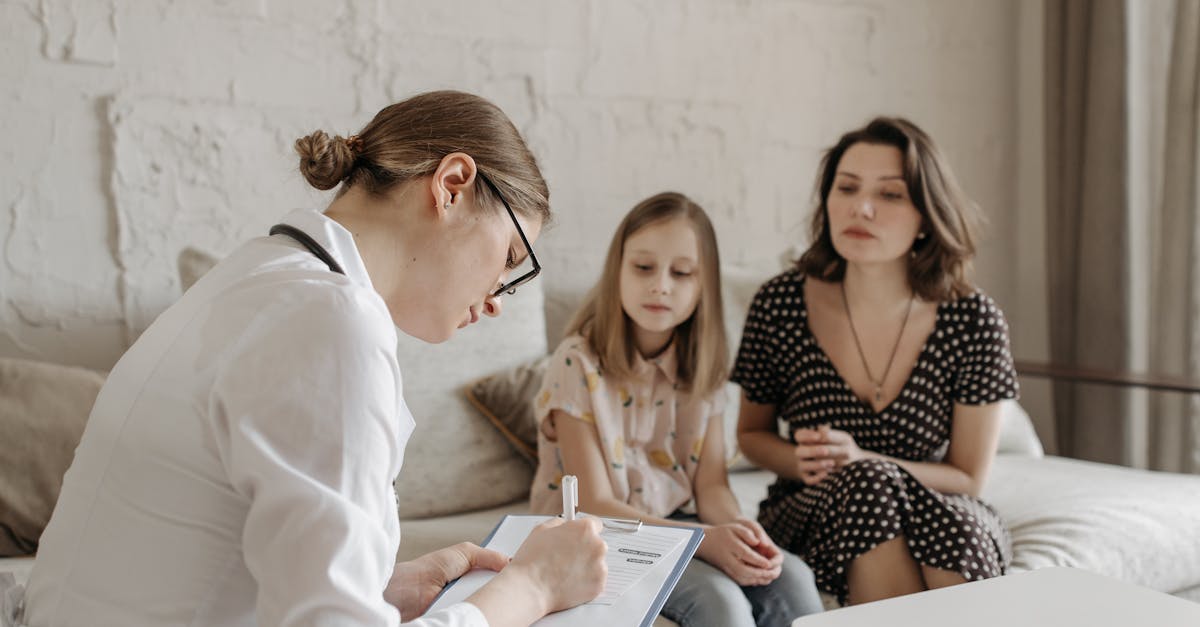 Mulher profissional escrevendo em prancheta durante atendimento a uma mãe e sua filha em um ambiente acolhedor. — Foto: Pavel Danilyuk