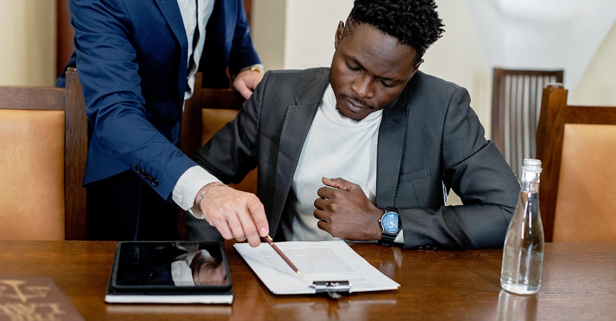 Dois homens em trajes formais analisando e apontando para documentos sobre uma mesa de madeira em um escritório. — Foto: Mikhail Nilov