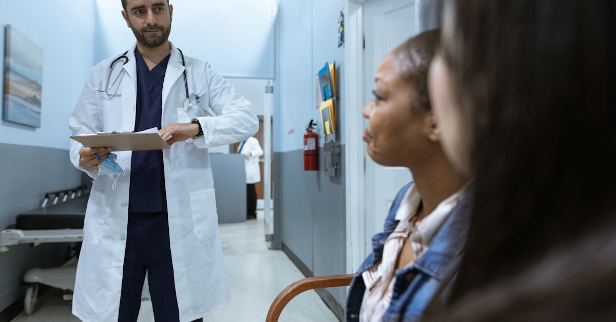 Médico de jaleco branco segurando prancheta e conversando com pacientes em um corredor de hospital. — Foto: RDNE Stock project