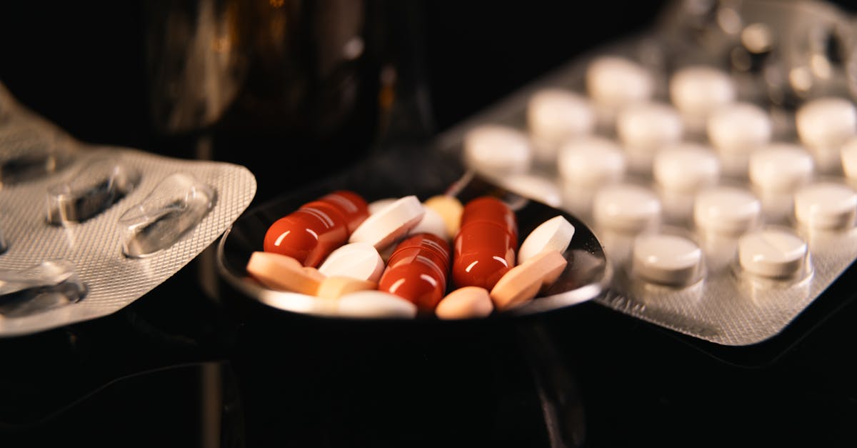 Diversos comprimidos e cápsulas coloridas em uma colher ao lado de cartelas de remédios em fundo escuro. — Foto: Bastian Riccardi