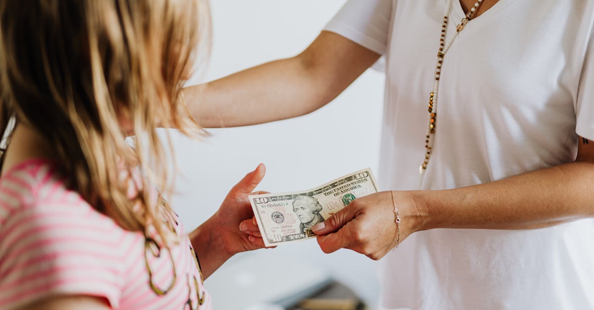 Uma mulher entregando uma nota de dólar para uma criança pequena em um ambiente doméstico. — Foto: www.kaboompics.com