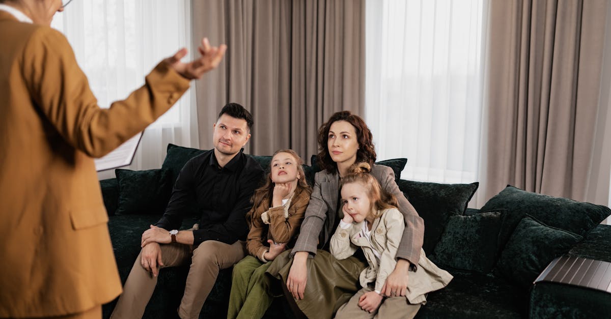 Profissional em blazer gesticulando para uma família sentada em um sofá durante uma consultoria. — Foto: Alena Darmel