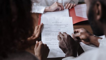 Pessoas em uma reunião analisando e segurando um documento jurídico sobre uma mesa de madeira. — Foto: Ron Lach