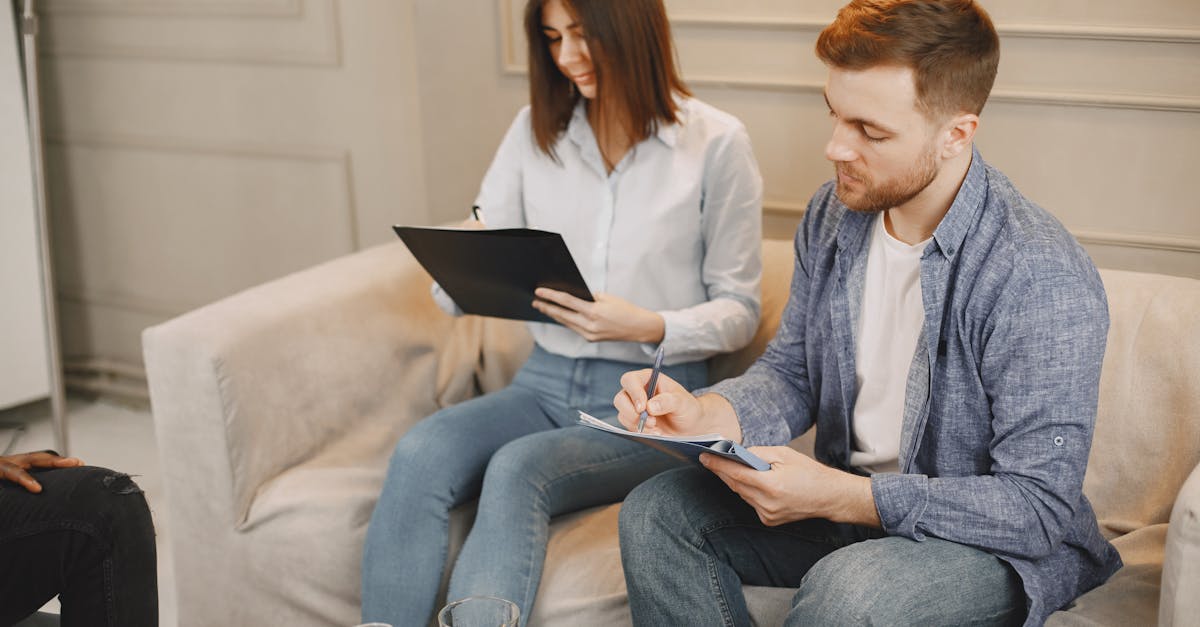 Homem e mulher sentados em um sofá assinando documentos em pranchetas durante uma reunião. — Foto: Gustavo Fring