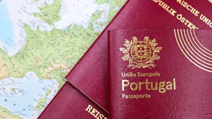 Passaportes europeus vermelhos sobre um mapa mundi colorido, com destaque para o passaporte de Portugal. — Foto: Marta Branco